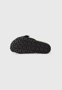 Semelle en caoutchouc noir avec un motif de vagues texturé, présentant un intérieur en liège et un design minimaliste. Pas de marquage ou d'ornementation visibles.