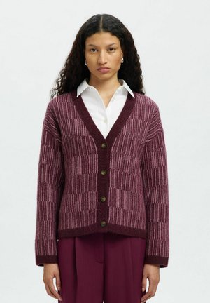 Burgundy-nahkahousu, jossa on oltavankärki, V-muotoinen kaula-aukko ja nappisulku. Sisältää kontrastoivia neulekuvioita ja hieman lyhennetyt hihat.