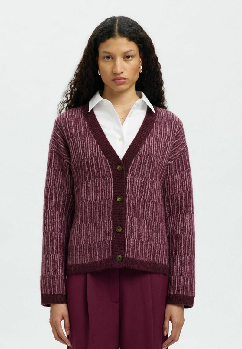 Bordowy kardigan o prążkowanej teksturze, z dekoltem w kształcie V i zapięciem na guziki. Posiada kontrastowe wzory dzianiny i lekko skrócone rękawy.