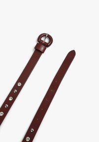 Cinturón de cuero marrón con tachuelas plateadas y una hebilla de metal redonda. Presenta una textura suave y múltiples agujeros de ajuste a lo largo de la correa.