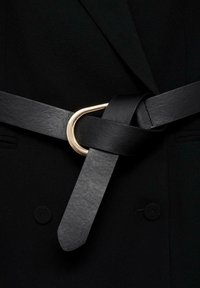 Schwarzer Leder Gürtel mit glatter Textur, der eine goldene Metallschnalle aufweist, die kunstvoll um sich selbst gedreht ist.