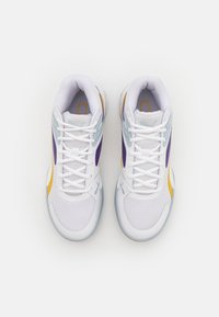 Chaussures de sport blanches avec une tige en mesh, présentant des accents violets, jaunes et bleu clair, ainsi qu'une semelle texturée. Conception à lacets avec branding.