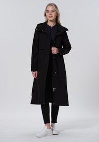 Cappotto lungo nero con cappuccio, zip frontale e bottoni a scatto. Presenta una tasca laterale, texture liscia e arriva sotto le ginocchia.