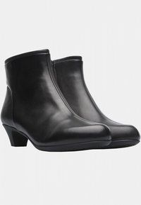 Musthave mustad musta nahast säärised, madala kontsaga, sileda pealispinnaga, ümmarguse ninaga ja külgosa tõmbelukuga. Lihtne disain, millel on minimaalsed aktsendid.