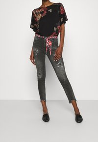 Černá blůzka s krátkým rukávem a květinovým vzorem. Doby černé džíny s obroušeným lemem a květinovým páskem. Černé baleríny doplňují celý outfit.