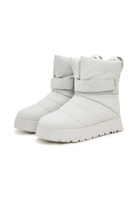 Svijetlosive, podstavljene gležnjače s debelim potplatom i širom trakom preko gornjeg dijela. Sadrže šivane detalje i strukturirane bočne strane.