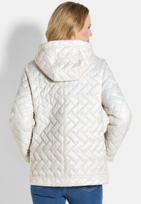 Leichte gesteppte Jacke in Weiß, mit Kapuze, diagonalen Mustern und lockerer Passform. Geeignet für die Freizeit.