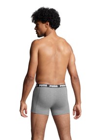 Gray boxer shorts with a black Puma logo band, made of soft material. The design features a snug fit and a mid-rise cut.