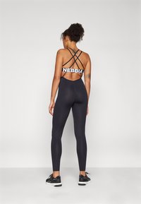 Conjunto desportivo preto com um design de costas cruzadas e um grande logótipo da NEBBIA. O tecido tem uma textura suave, forma ajustada e leggings de comprimento completo.