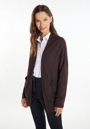 Brauner gestrickter Cardigan mit Schalkragen, offenem Vorderteil und zwei Fronttaschen. Der Stoff wirkt weich, mit gerippten Bündchen und Saum.