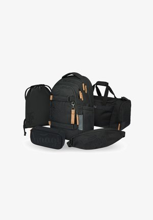 Set di zaini neri composto da uno zaino principale, una borsa da viaggio, un sacchetto con coulisse e un astuccio, tutti con un branding sottile e dettagli in pelle.