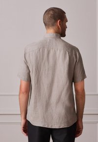 Kurzärmeliges, hellgraues Hemd mit Knopfleiste und feinem, strukturiertem Muster. Verfügt über einen Standardkragen und einen leicht abgerundeten Saum.