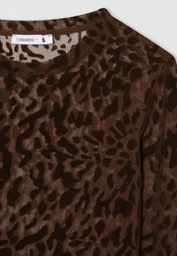 Top trasparente marrone con motivo animalier in diverse sfumature di marrone scuro. Texture morbida e scollatura rotonda. Etichetta del marchio: Terranova.