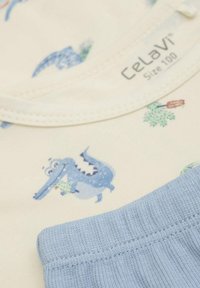 Baumwoll-T-Shirt mit einem elfenbeinfarbenen Grundton und blauen Krokodilillustrationen. Mit einem hellblauen Saum und dem Markenlabel 'Celavi', Größe 100.