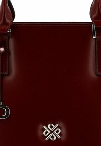 Bolso tote de cuero burdeos con forma estructurada, detalles en metal plateado y logotipo grabado en el centro, con textura suave y detalles de costura.