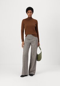 Smeđi turtleneck pulover, sivi široki karirani hlače, crne cipele i zeleni ručni torba. Vidljive su čvrste boje i teksturirani uzorci.