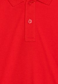 Rode katoenen polo met een gemêleerd weefpatroon, voorzien van een drie-knopenlijst en een klassieke kraag voor een casual uitstraling.