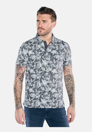 Short-sleeve polo shirt in dark gray featuring a white floral pattern, a buttoned collar, and a textured fabric. It's paired with blue jeans.
