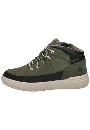 Baskets mi-hautes vert olive et noir avec semelle beige clair, lacets à l’avant, col matelassé à la cheville et logo embossé sur le côté du talon.