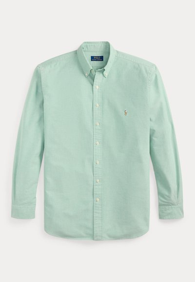 Gai zaļš kokvilnas krekls ar pogām, garām piedurknēm, apkakles izgriezumu un mazu izšūtu logo kreisajā krūtīs.