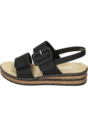 Sort sandal med justerbar spændelukning og rem, beige polstret indersål og lagdelt korksål med sort gummiydersål.