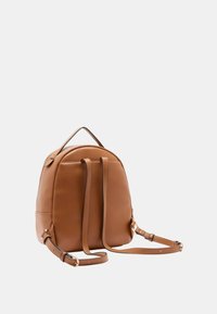 Zaino in pelle marrone con una forma arrotondata, texture liscia, spallacci regolabili e un manico superiore, caratterizzato da un motivo di cucitura sottile.