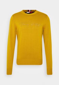 Gelber Strickpullover mit Rundhalsausschnitt, mit gesticktem "Tommy Hilfiger" Logo auf der Brust sowie gerippten Bündchen und Saum.
