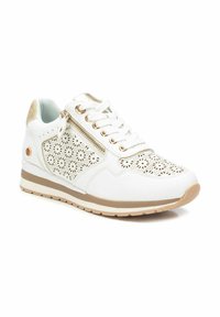 Zapatillas blancas con un diseño floral perforado, detalles metálicos, cordones en la parte delantera y una cremallera lateral en una suela acolchada con una franja marrón.