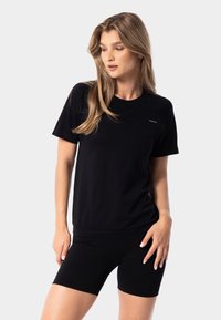 Sort bomulds-t-shirt med korte ærmer og rund hals, med en diskret logo-detalje, parret med matchende sorte cykelshorts.