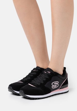 Zapatillas deportivas negras con material de ante y sintético, con acentos en rosa, una suela texturizada y un diseño de cordones.