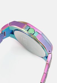 Montre en métal multicolore avec une finition dégradée arc-en-ciel, boîtier rectangulaire, dos en acier inoxydable et bracelet texturé avec fermeture à clapet.