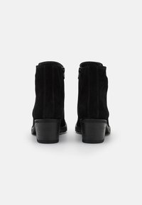 Μαύρες σουέτ μπότες μέχρι τον αστράγαλο με στρογγυλή μύτη, διακοσμητική ραφή και χοντρό τακούνι; πλαϊνές φερμουάρ για ευκολία.