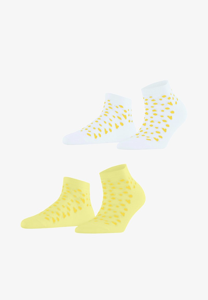 Deux paires de chaussettes de cheville, une blanche et une jaune, toutes deux avec des motifs dispersés de cœurs jaunes et de points.