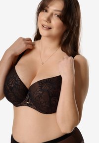 Czarny koronkowy stanik z kwiatowym wzorem, z fiszbinami oraz małym złotym akcentem na środku. Miękka faktura z regulowanymi ramiączkami.