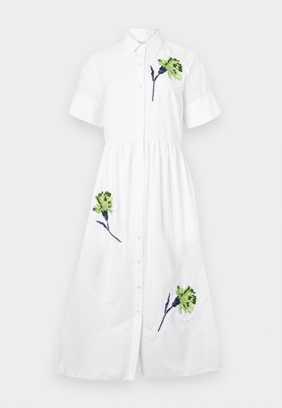 Valge särgimekko lühikeste varrukatega, nööpidega ees, kokku volditud talje ning rohelise ja sinise lilleline tikand vasakul rinnal ja alläärs.