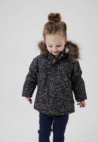 Dunkelblaues, floral gemustertes, puffiges Jacket mit Kapuze aus Kunstfell, ausgestattet mit einem Reißverschluss und elastischen Bündchen, kombiniert mit dunkelblauen Hosen.
