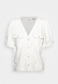 Blouse blanche à manches courtes avec un col en V profond, fermeture à boutons et deux poches poitrine. Confectionnée en coton doux avec des manches légèrement bouffantes.