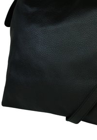 Zwarte leren handtas met een textuur oppervlak, een zachte vorm en een lange schouderband, met minimale hardware voor een elegante uitstraling.