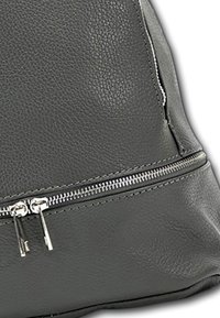 Sac en cuir gris avec une surface texturée, doté d'une fermeture éclair et de quincaillerie en argent, mettant en avant des lignes épurées et un design minimaliste.