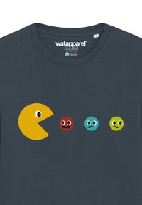 T-shirt en coton bleu marine avec un graphique de Pac-Man jaune avec des yeux, suivi de trois points colorés ayant différentes expressions faciales.
