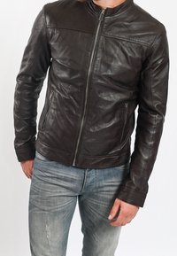 Brun läderjacka med dragkedja fram, ståkrage och två sidofickor. Materialet är slätt med en lätt rynkad textur.