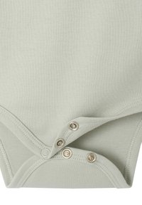 Hellgrüner Babystrampler mit drei teilweise geöffneten Metalldruckknöpfen am unteren Saum für einen einfachen Zugang zur Windel.