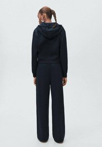 Black cropped sweatshirt with a hood, paired with wide-leg pants. Fabric appears soft, with a smooth texture and minimal detailing.