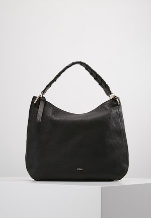 Sort tekstureret læderhåndtaske med flettet håndtag og lille sølv Furla-logo foran, udstillet på en hvid piedestal.