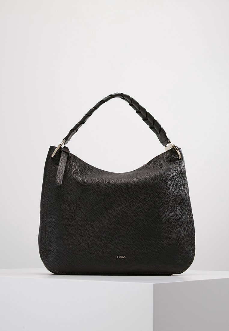 Sac à main en cuir noir texturé avec poignée tressée et petit logo Furla argenté sur le devant, exposé sur un socle blanc.