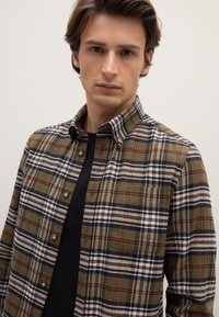 Kariertes Hemd mit Knöpfen in Olivgrün, Marineblau und Weiß; verfügt über einen klassischen Kragen und eine Brusttasche; baumwollähnliche Textur mit entspanntem Schnitt.