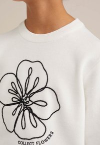 White sweater with a round neckline, featuring an embroidered black flower design and the text "COLLECT FLOWERS" below. Soft texture.