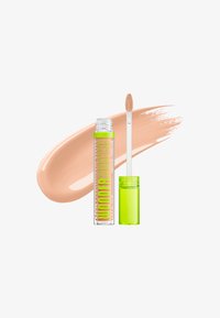 Tube de correcteur ouvert avec bouchon vert citron et applicateur, échantillon de correcteur beige derrière sur fond blanc.
