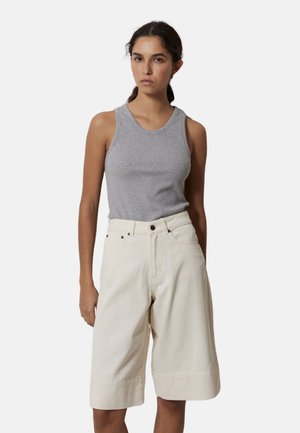 Top sin mangas gris combinado con pantalones cortos beige hasta la rodilla, con un ajuste holgado y costuras visibles en el dobladillo.