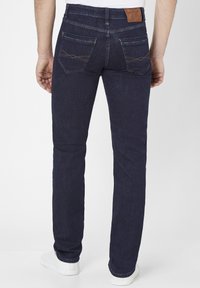 Donkerblauwe denim jeans met een slim fit, voorzien van twee achterzakken met decoratieve stiksels en een bruine leren label aan de tailleband.